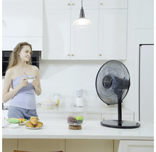 Ventilateur de table dans une cuisine lumineuse avec une femme tenant une tasse