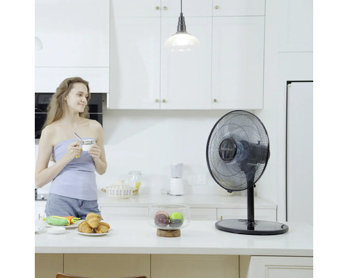 Ventilateur de table dans une cuisine lumineuse avec une femme tenant une tasse