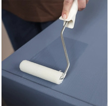 Eine Person streicht mit einer Farbwalze eine Oberfläche.