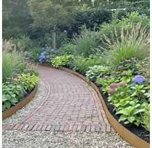 Gartenweg mit Ziegelsteinen, umrandet von Pflanzen und Rasenkanten