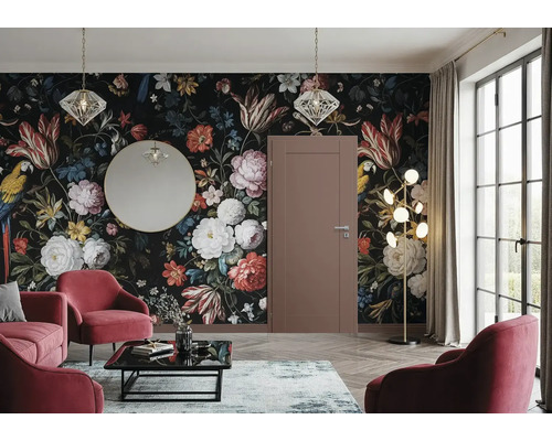 Salon avec papier peint floral, porte, miroir, suspensions, lampadaire, tapis, table basse et fauteuils