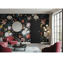 Salon avec papier peint floral, porte, miroir, lampadaire et fauteuils rouges