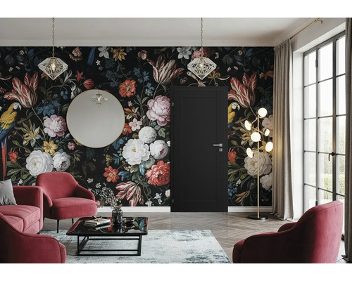 Salon avec papier peint floral, porte, miroir, lampadaire et fauteuils rouges