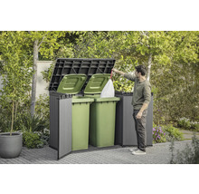 Mülltonnenbox mit Mann, der einen Müllsack hineinwirft, im Garten