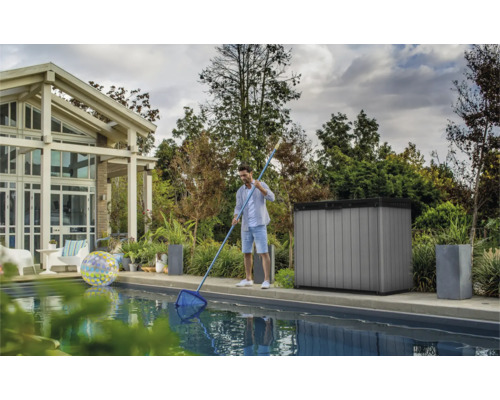 Szene eines Mannes, der einen Pool mit einem Kescher reinigt, im Hintergrund ein Poolhaus und ein Gartenschrank