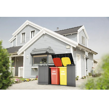 Mülltonnenbox mit drei Mülltonnen vor einem Haus