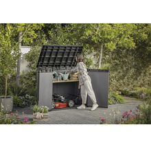 Offene Gartenbox mit Gartengeräten und Rasenmäher im Garten