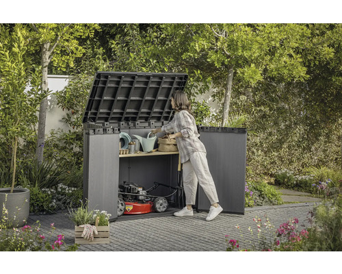 Offene Gartenbox mit Gartengeräten und Rasenmäher im Garten