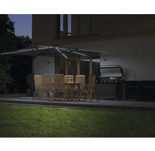 Jardin avec salle à manger sous un parasol éclairé et un barbecue