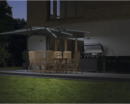 Jardin avec salle à manger sous un parasol éclairé et un barbecue