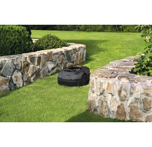 Robot tondeuse à gazon sur une pelouse entre deux murs de pierre