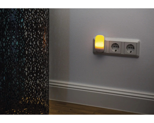 Nachtlicht in Steckdose neben dekorativer Lampe