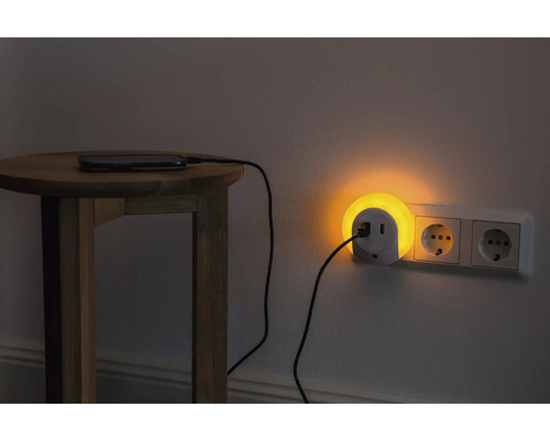 Nachttisch mit Smartphone, das über eine Steckdosenleuchte mit USB Anschluss geladen wird