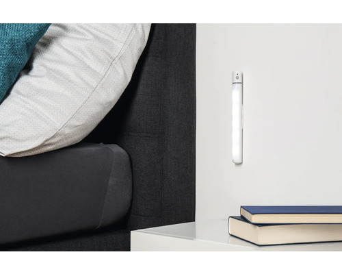 Szene mit einem Bett, Nachttisch, zwei Büchern und einer LED-Leuchte