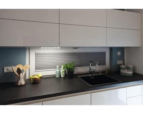 Moderne Küche mit weißen Schränken, dunkler Arbeitsplatte, Spüle und Küchenutensilien.