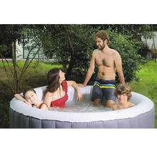 Une famille se détend dans un jacuzzi gonflable dans le jardin.