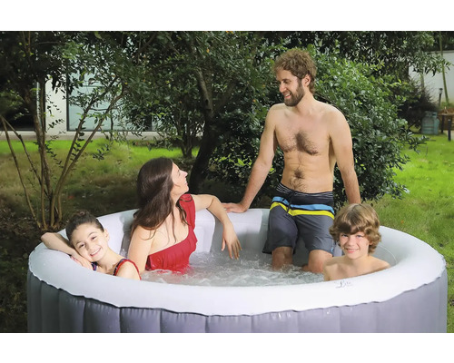 Une famille se détend dans un jacuzzi gonflable dans le jardin.