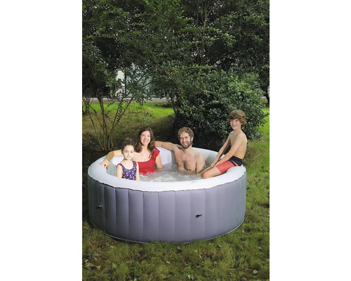 Une famille se détend dans un jacuzzi gonflable dans le jardin.
