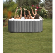 Trois personnes dans un jacuzzi gonflable dans le jardin, les mains en l'air