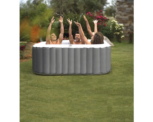 Trois personnes dans un jacuzzi gonflable dans le jardin, les mains en l'air