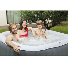 Une famille se détend dans un jacuzzi gonflable dans le jardin.