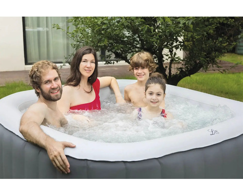 Une famille se détend dans un jacuzzi gonflable dans le jardin.