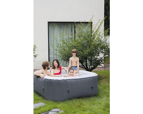 Famille se détendant dans un bain à remous gonflable dans le jardin.