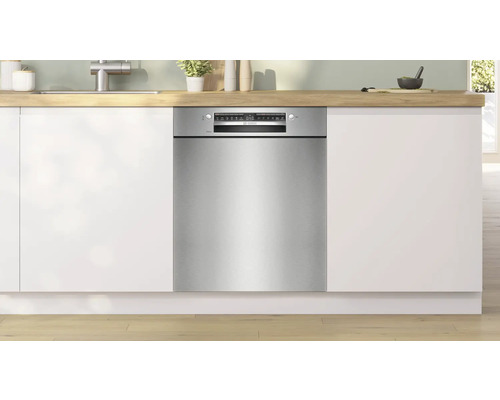 Lave-vaisselle intégré dans une cuisine moderne avec des armoires blanches et un plan de travail en bois.
