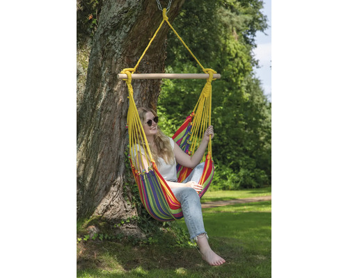 Frau entspannt in einer farbenfrohen Hängesessel-Schaukel, die an einem Baum befestigt ist.