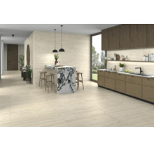 Pièce lumineuse avec kitchenette, table de bar avec tabourets de bar et carrelage.