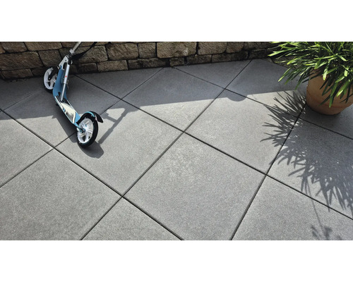 Dalles en béton posées à l'extérieur avec trottinette et plante