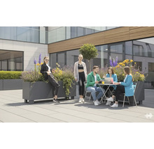 Personen sitzen und stehen im Aussenbereich an Tischen und Pflanzenkübeln.