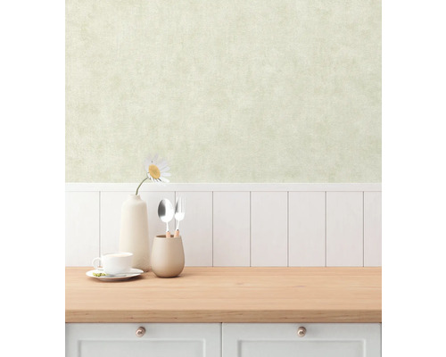 Innenraumszene mit einer Arbeitsplatte, Geschirr und einer Vase mit einer Blume vor einer Wand