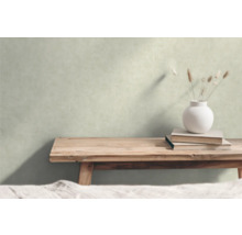Dekorative Szene mit einer Holzbank, Büchern und einer Vase mit Gräsern vor einer Wand