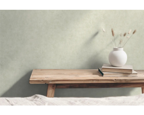 Dekorative Szene mit einer Holzbank, Büchern und einer Vase mit Gräsern vor einer Wand