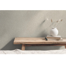 Nahaufnahme einer strukturierten Tapete im Innenraum mit Holzbank, Büchern und Blumenvase als Dekoration.