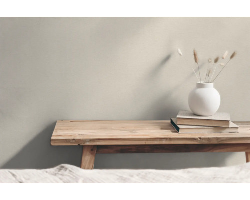 Helle Einrichtung mit Holztisch, Büchern und einer Vase mit Trockenblumen.