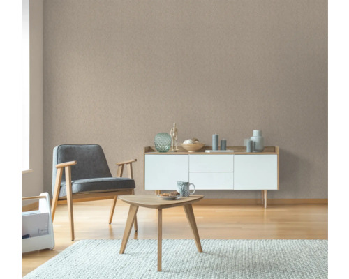 Wohnzimmer mit Sessel, Tisch und Sideboard vor einer Strukturtapete