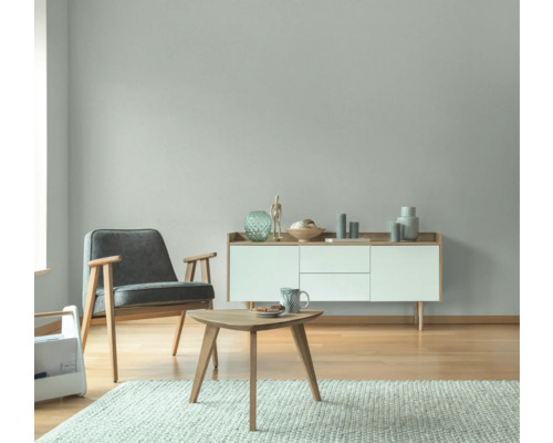 Wohnzimmer mit Sessel, Kommode, Tisch und Teppich in hellem Design