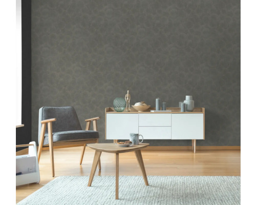 Wohnzimmer mit Sessel, Beistelltisch und Kommode vor einer strukturierten Wandtapete.