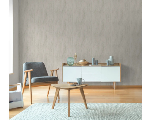 Wohnzimmer mit gemusterter Tapete, Sessel, Tisch und Kommode