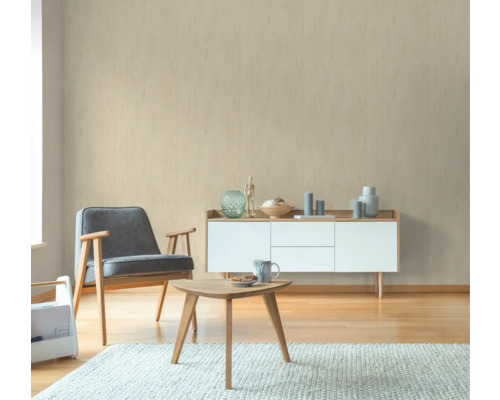 Wohnzimmer mit Sessel, Tisch und Sideboard vor einer beigen Wand