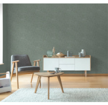 Wohnzimmer mit Sessel, Beistelltisch und Kommode vor einer grünen Wandtapete