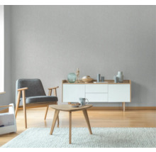 Wohnzimmer mit Sessel, Beistelltisch und Sideboard vor einer strukturierten Tapete