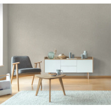 Wohnzimmer mit Sessel, Couchtisch, Sideboard und gemusterter Tapete
