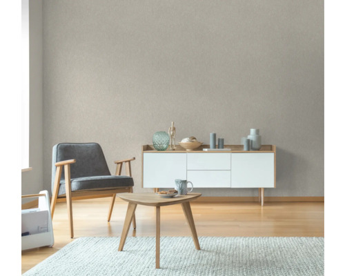 Wohnzimmer mit Sessel, Couchtisch, Sideboard und gemusterter Tapete