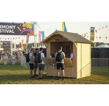 Scène de festival avec stand de billetterie et personnes qui attendent.