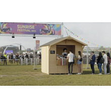 Petite maison de jardin en bois lors d'un événement musical avec une file d'attente devant
