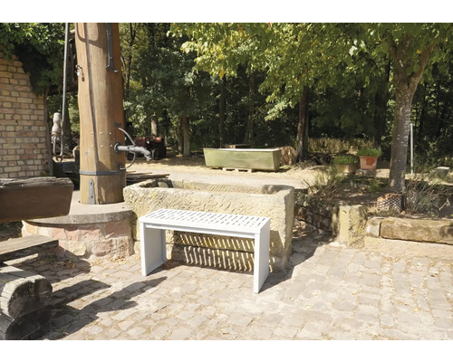 Gartenansicht mit Steinbrunnen und einer weißen Bank