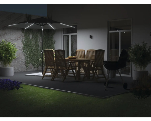 Parasol de jardin éclairé au-dessus d'un salon de jardin en bois et d'un barbecue sur une terrasse